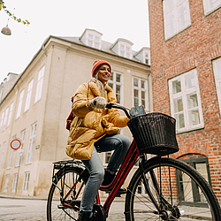 Eine Frau in Winterkleidung sitzt auf einem Fahrrad. Sie lächelt.