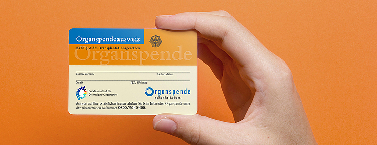 Organspendeausweis vor orangefarbenem Hintergrund - Symbol für Organspende und die Entscheidung, Leben zu retten.