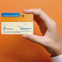 Organspendeausweis vor orangefarbenem Hintergrund - Symbol für Organspende und die Entscheidung, Leben zu retten.