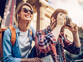 Pärchen im Urlaub mit Sonnenbrille und Kamera.