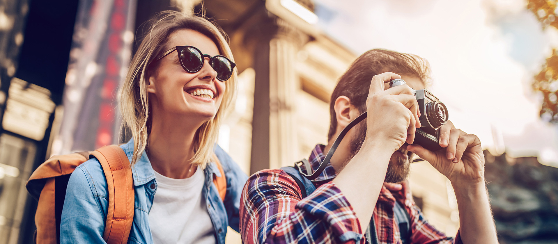 Junge Frau mit Sonnenbrille und Mann mit Kamera schauen in die Ferne