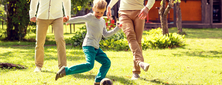 Vater spielt mit Sohn Fussball im Garten