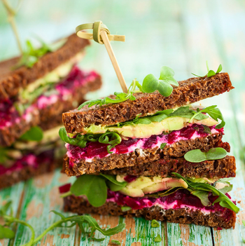 Ein gesundes Sandwich belegt mit Salat, Avocado und roter Beete.